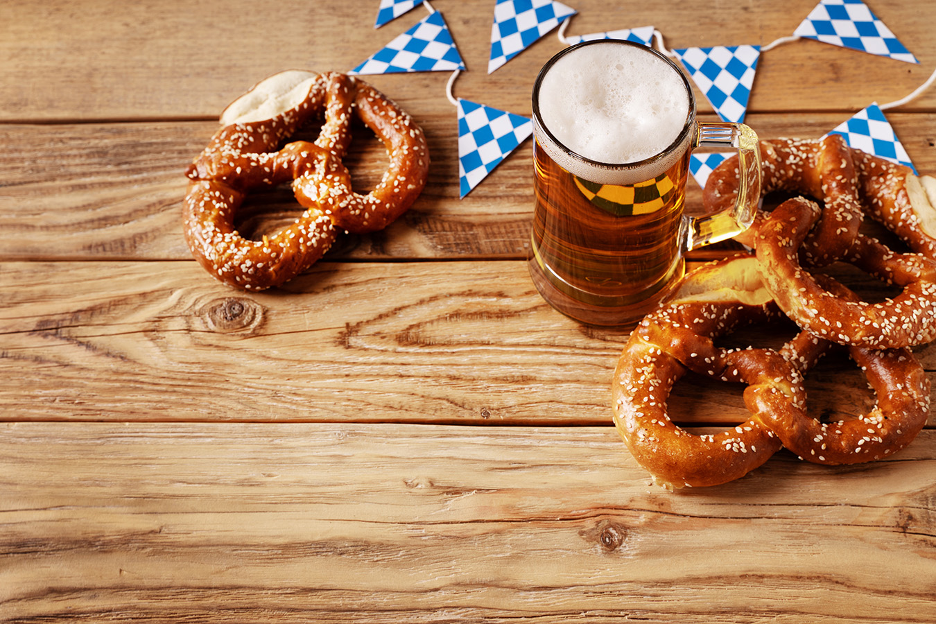 GettyImages-2154755506s Beer and pretzel with decorative Bavarian flags in the background